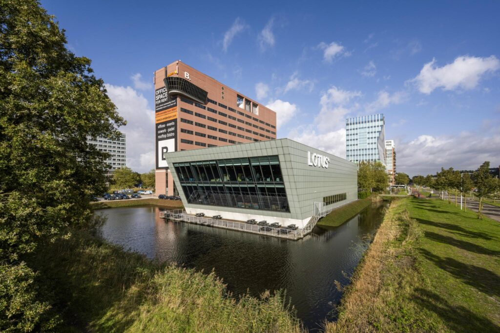 Modern kantoorgebouw 'Lotus' aan het water op de Johan Huizingalaan in Amsterdam, met op de achtergrond het grote B-Building bedrijfsverzamelgebouw.
