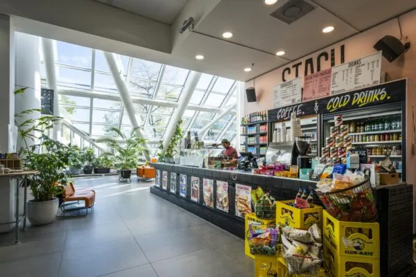 Moderne koffiebar STACH aan de Johan Huizingalaan met grote raampartijen, veel planten en een uitgebreid assortiment aan drankjes en snacks.