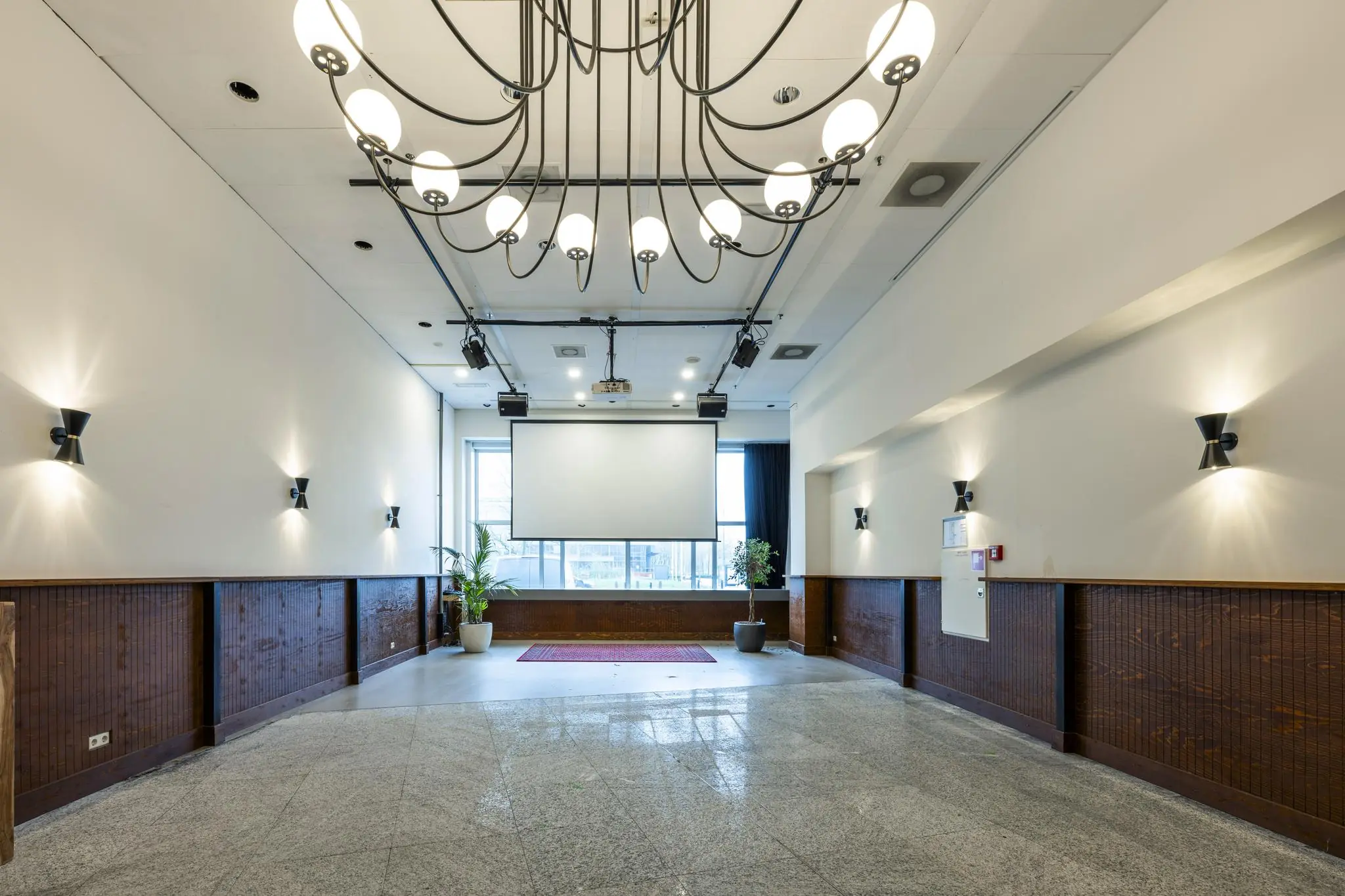 Vergaderruimte aan de Johan Huizingalaan met een groot projectiescherm, moderne verlichting en planten bij het raam.