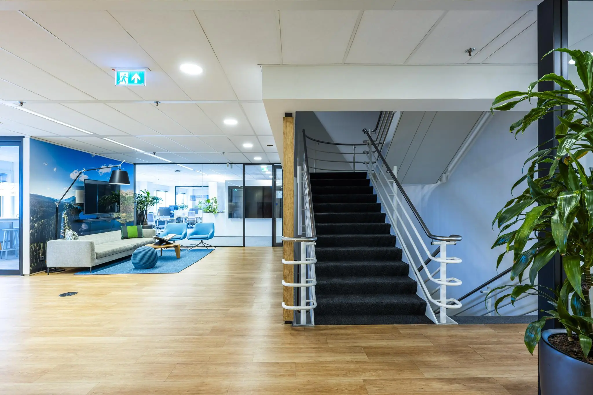 Moderne kantoorruimte aan de Johan Huizingalaan met een wachtruimte, open werkplekken en een trap naar boven.