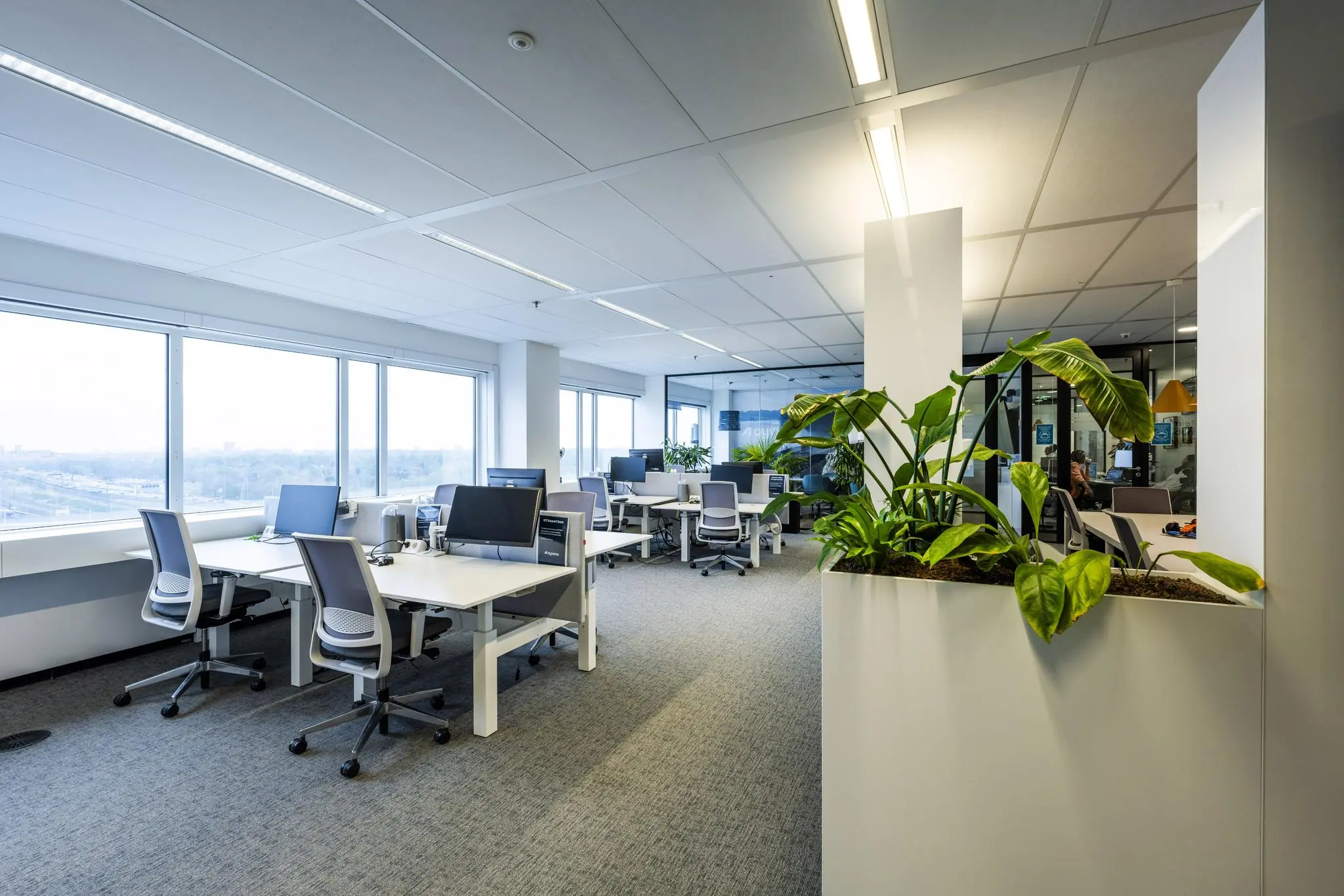 Modern kantoorinterieur aan de Johan Huizingalaan met open werkplekken, grote ramen en veel groen.
