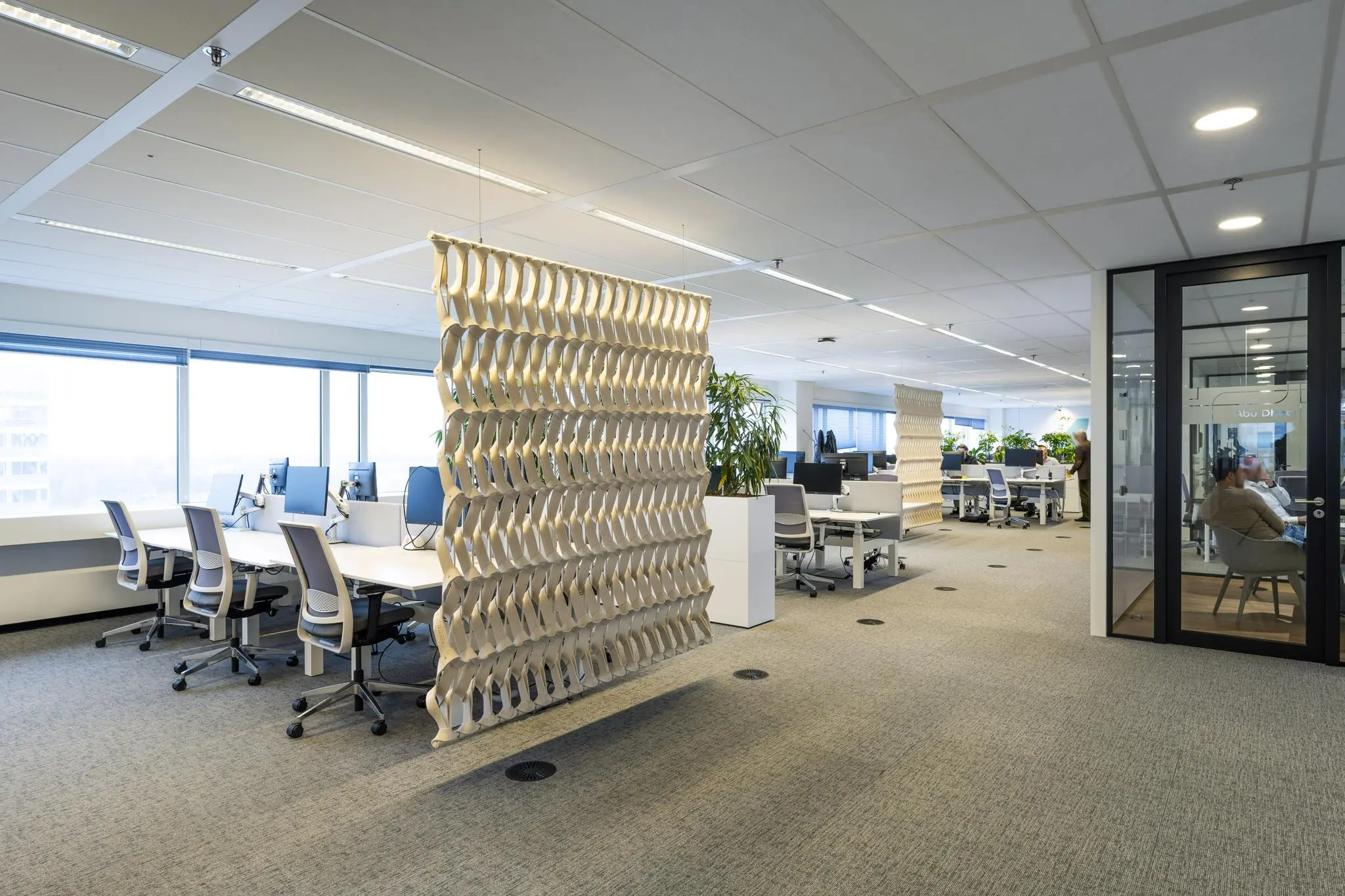 Modern kantoorinterieur aan de Johan Huizingalaan met flexplekken, planten en decoratieve roomdividers.