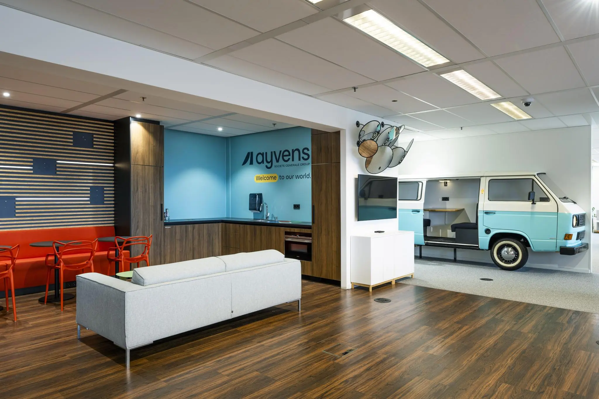Moderne kantoorlounge van Ayvens aan de Johan Huizingalaan met zithoek, koffiecorner en vergaderruimte in een halve retro Volkswagenbus.