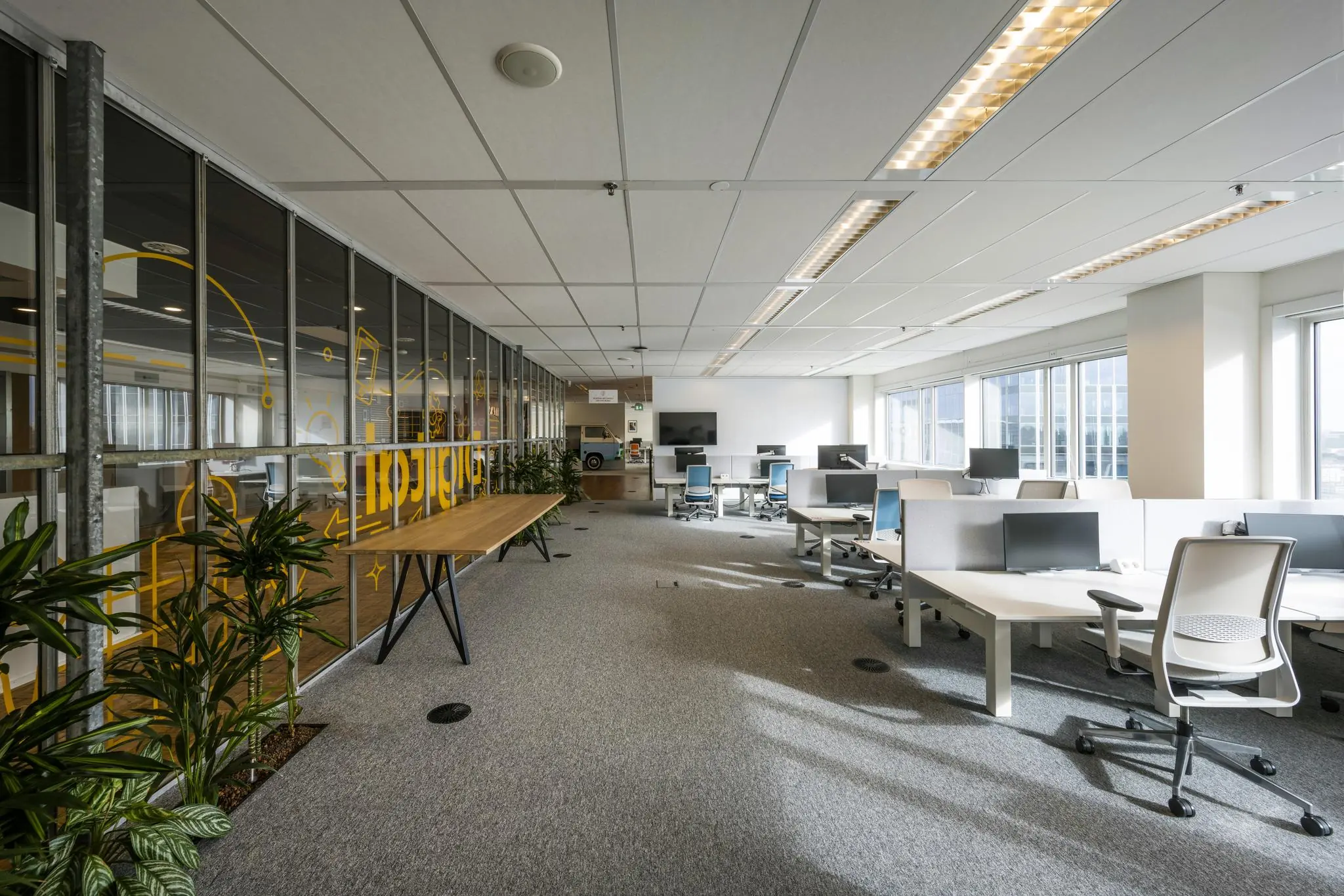 Moderne, lichte kantoorruimte aan de Johan Huizingalaan met werkplekken, bureaustoelen en computers.