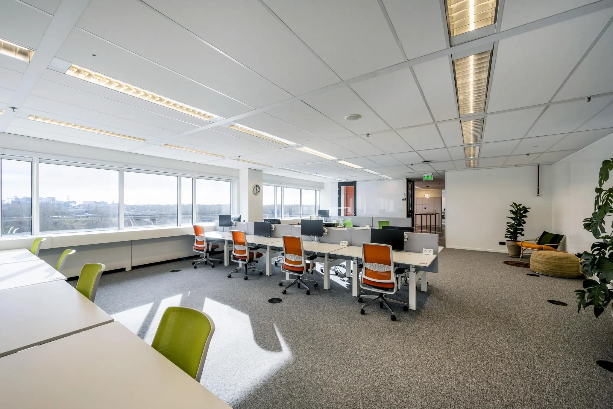 Modern kantoorinterieur aan de Johan Huizingalaan met werkplekken, bureaustoelen en grote ramen met uitzicht op de stad.