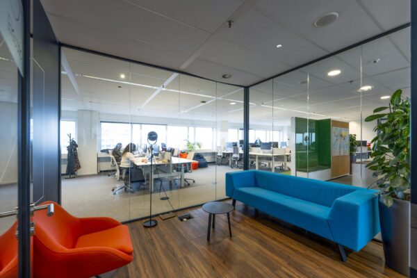 Moderne kantoorruimte aan de Johan Huizingalaan met glazen wanden, open werkplekken en een kleurrijke wachtruimte.