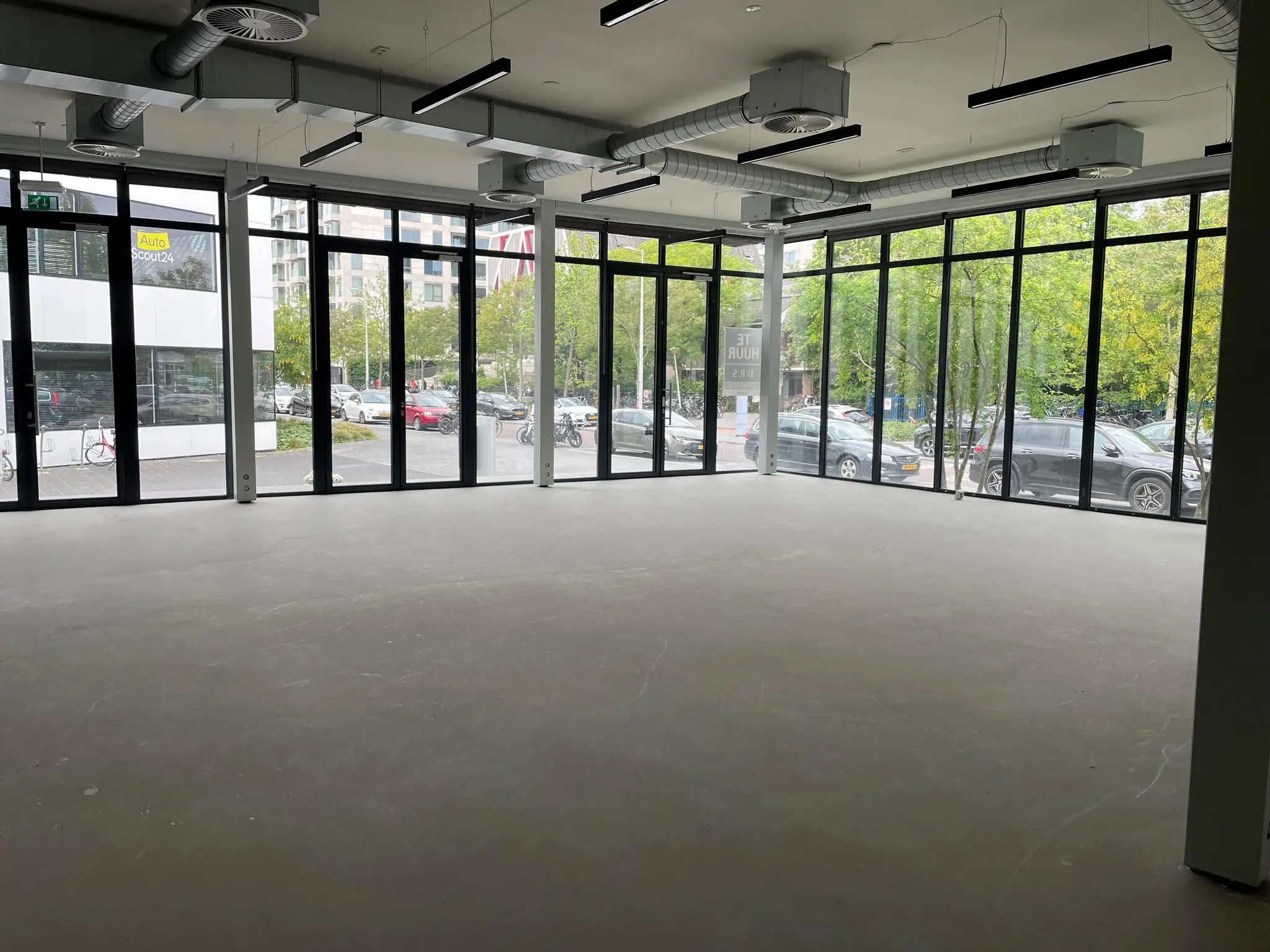 Leeg bedrijfs- of winkelpand met grote raampartijen aan de Fred. Roeskestraat met uitzicht op geparkeerde auto's en omliggende kantoren.