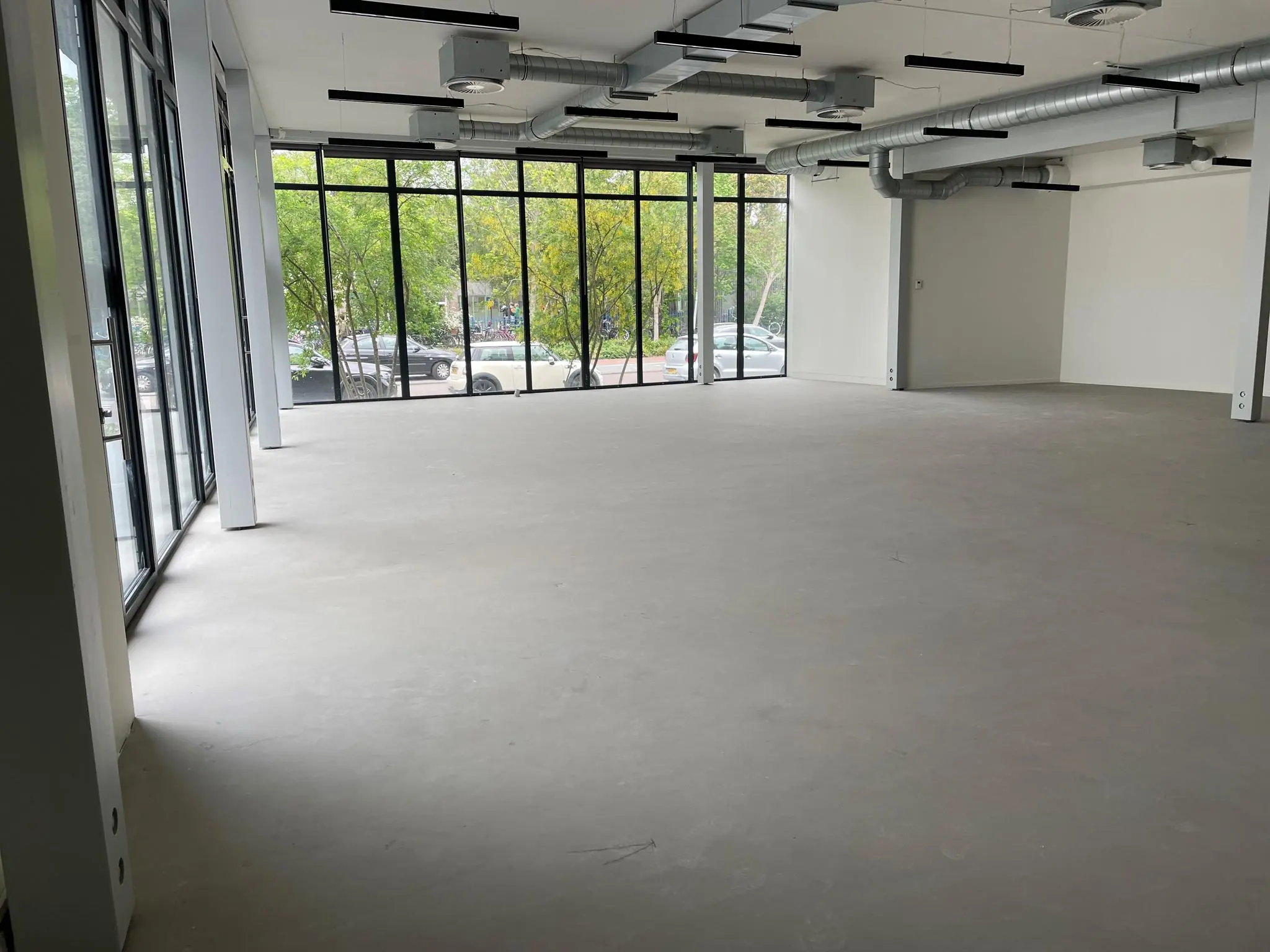 Leeg kantoorpand met betonnen vloer en grote ramen aan de Fred. Roeskestraat.