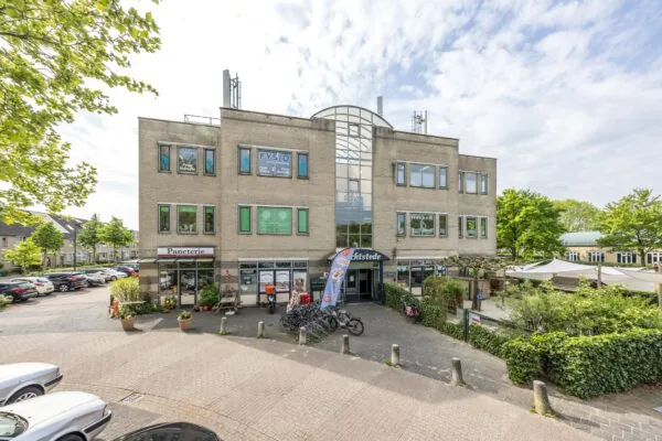 Vooraanzicht van een modern bedrijfsverzamelgebouw aan de Buitenweg met onder andere een fysiopraktijk, lunchroom en winkels.
