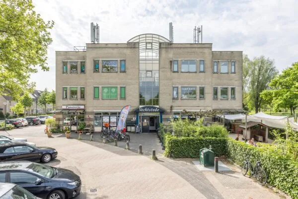 Vooraanzicht van het gebouw Vechtsstede aan de Buitenweg, met verschillende praktijken en winkels zoals een tandarts, fysiotherapie, paneterie en buitenterras.