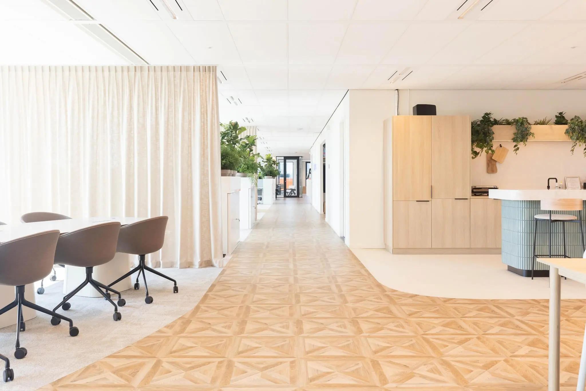 Licht en modern kantoorinterieur aan de Mt. Lincolnweg met houten vloer, open werkplekken en een keukenhoek.