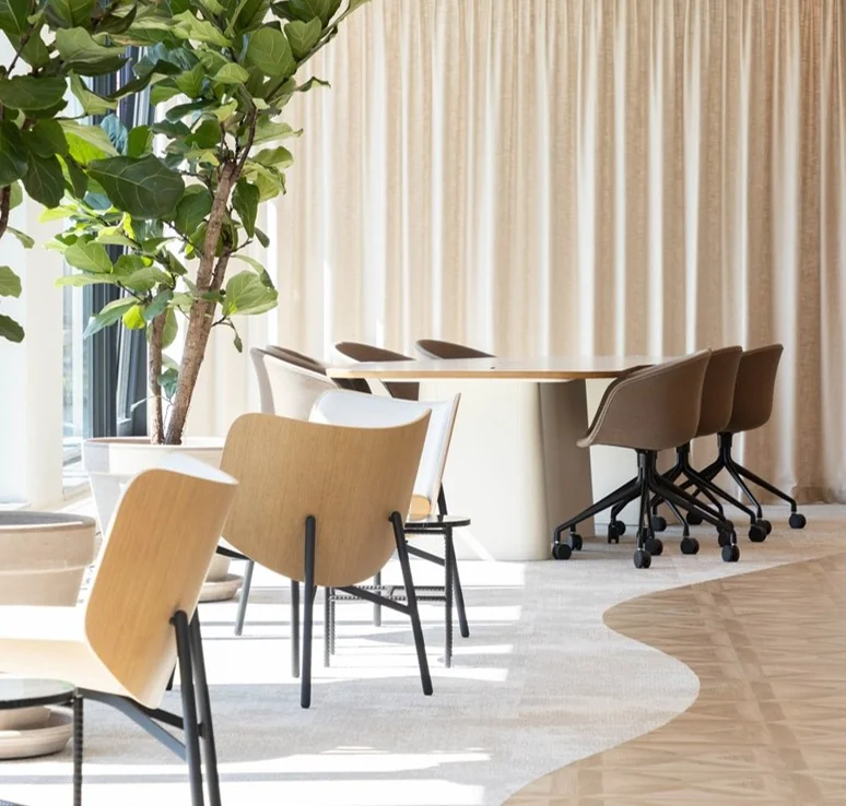 Moderne en lichte vergaderruimte aan de Mt. Lincolnweg met houten stoelen, ronde tafel en grote kamerplanten.