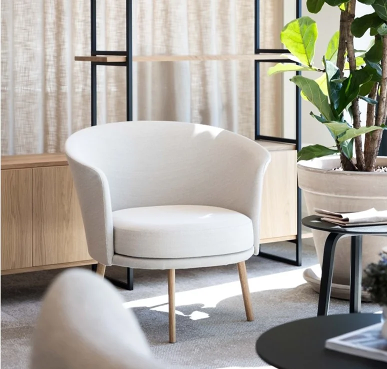 Lichtgrijze moderne fauteuil met houten poten in een minimalistisch interieur aan de Mt. Lincolnweg.