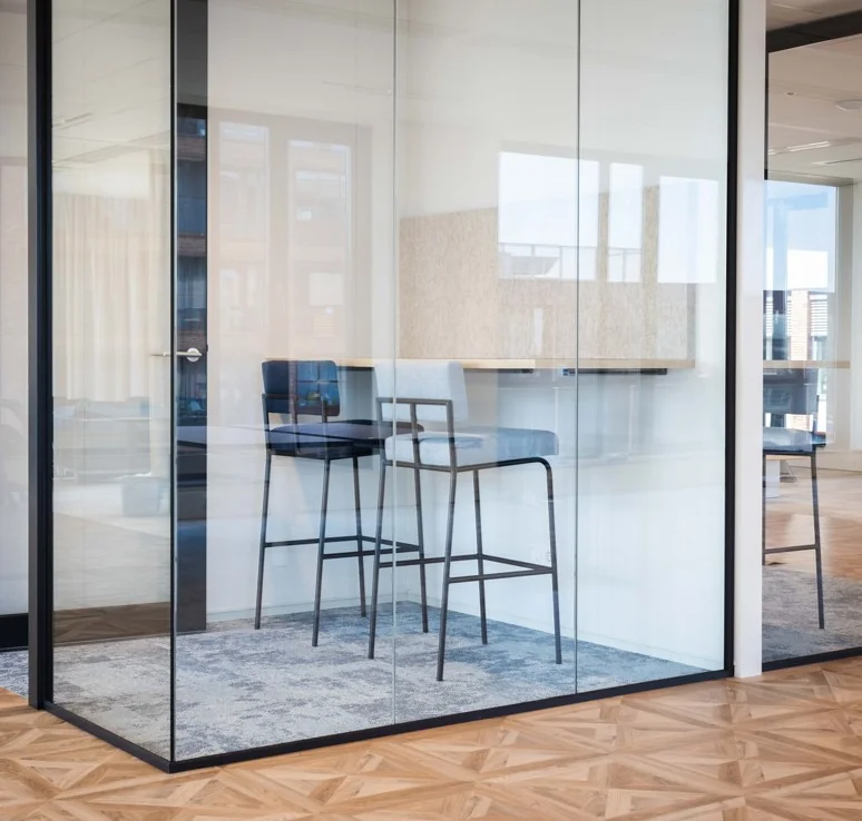 Moderne glazen vergaderruimte aan de Mt. Lincolnweg met hoge stoelen en een wandtafel.