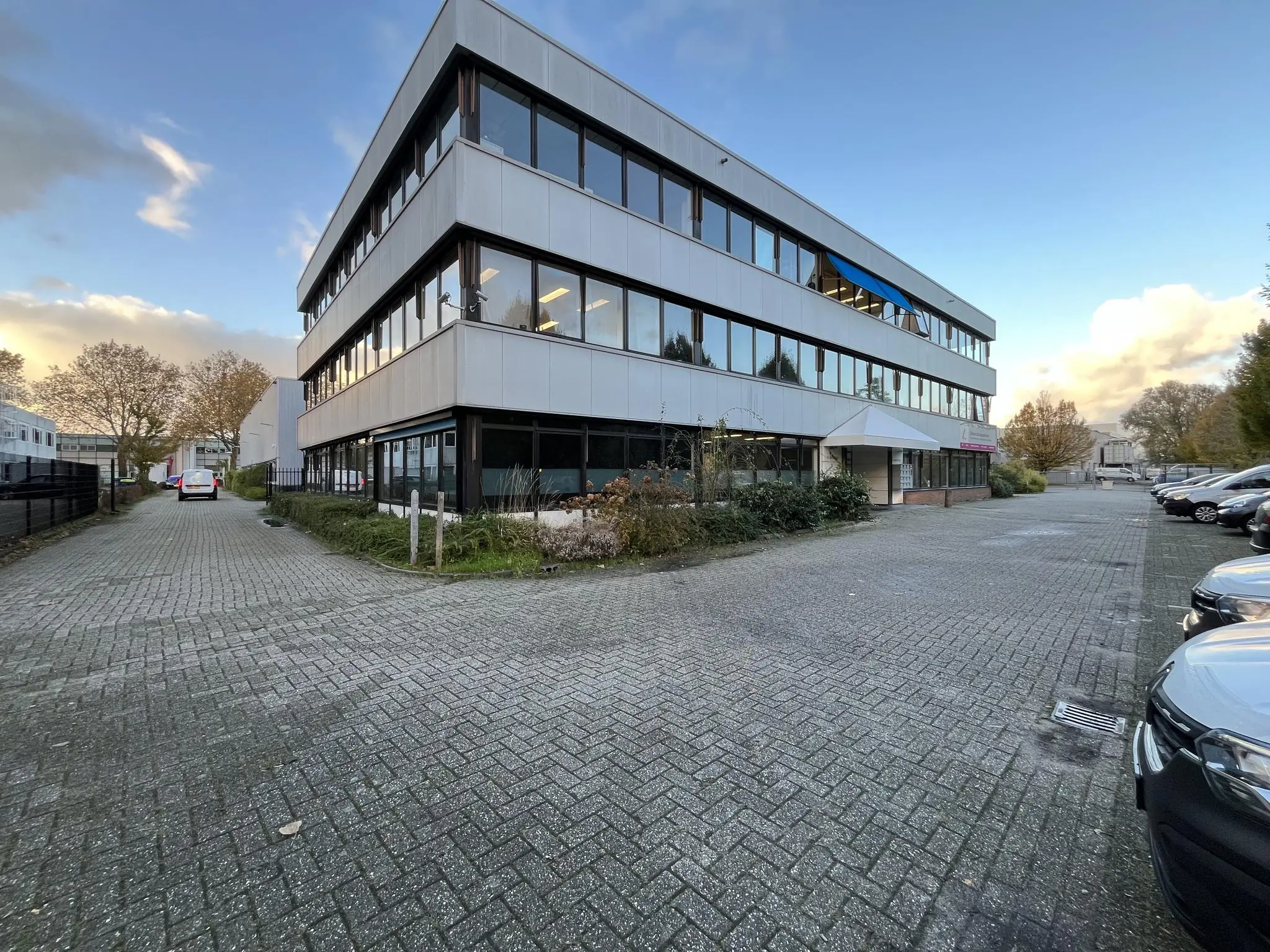 Kantoorgebouw aan de Industrieweg met parkeerplaatsen en omliggende bedrijvigheid.
