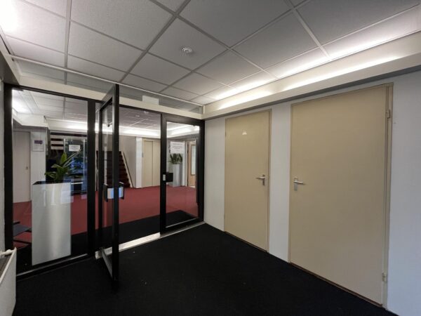 Hal met glazen toegangsdeuren en beige binnendeuren in een bedrijfspand aan de Industrieweg.