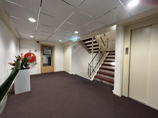 Hal met trap, lift, een deur met het bord “Incase” en een brandslanghaspel op Industrieweg 174.