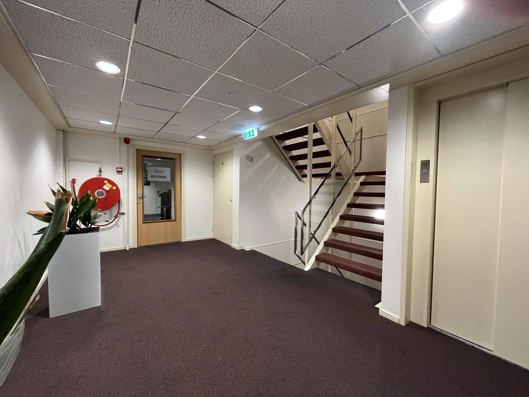 Hal met trap, lift, een deur met het bord “Incase” en een brandslanghaspel op Industrieweg 174.