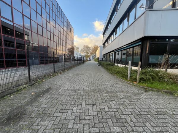 Een lege, met klinkers betegelde straat tussen twee moderne bedrijfsgebouwen aan de Industrieweg.