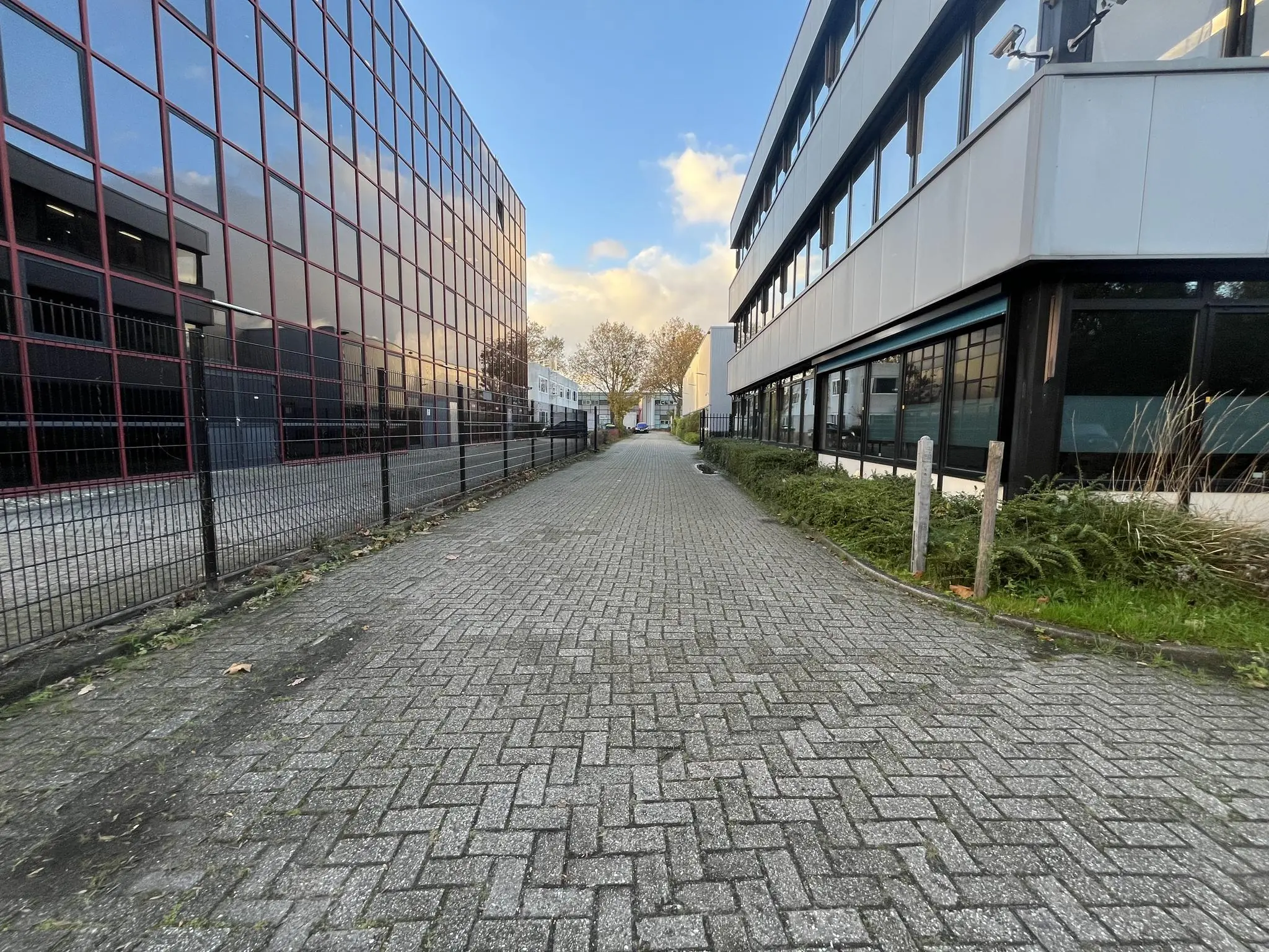 Een lege, met klinkers betegelde straat tussen twee moderne bedrijfsgebouwen aan de Industrieweg.