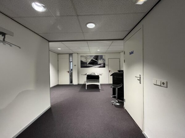 Zakelijke kantoorhal met een printer, een toiletdeur en een zwart-wit foto aan de muur aan de Industrieweg.