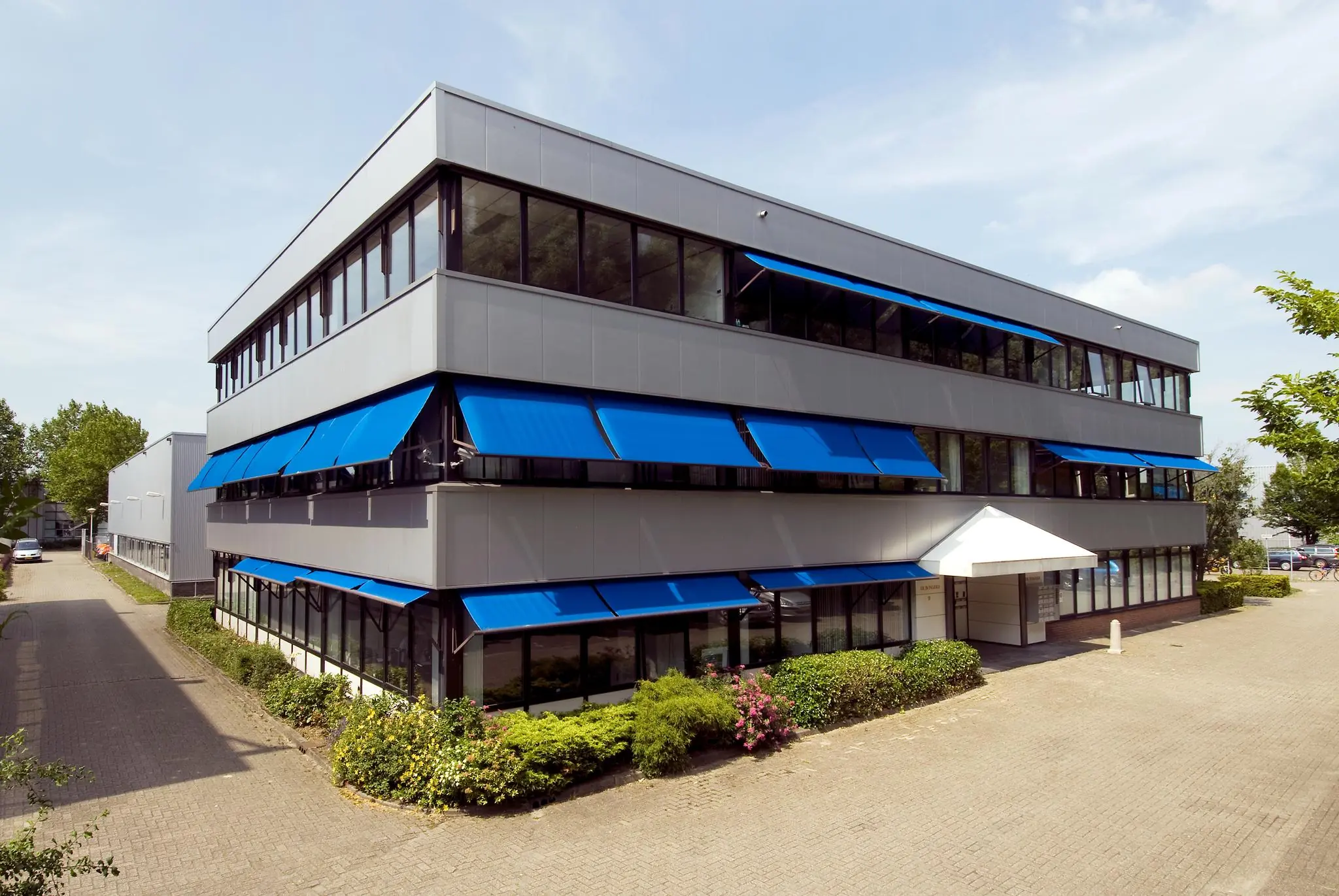 Kantoorpand aan de Industrieweg met blauwe zonwering en moderne gevel.