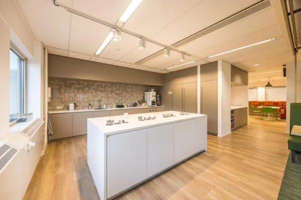Moderne kantoorpantry aan de Varrolaan met kookeiland, koffieautomaat en zithoek.
