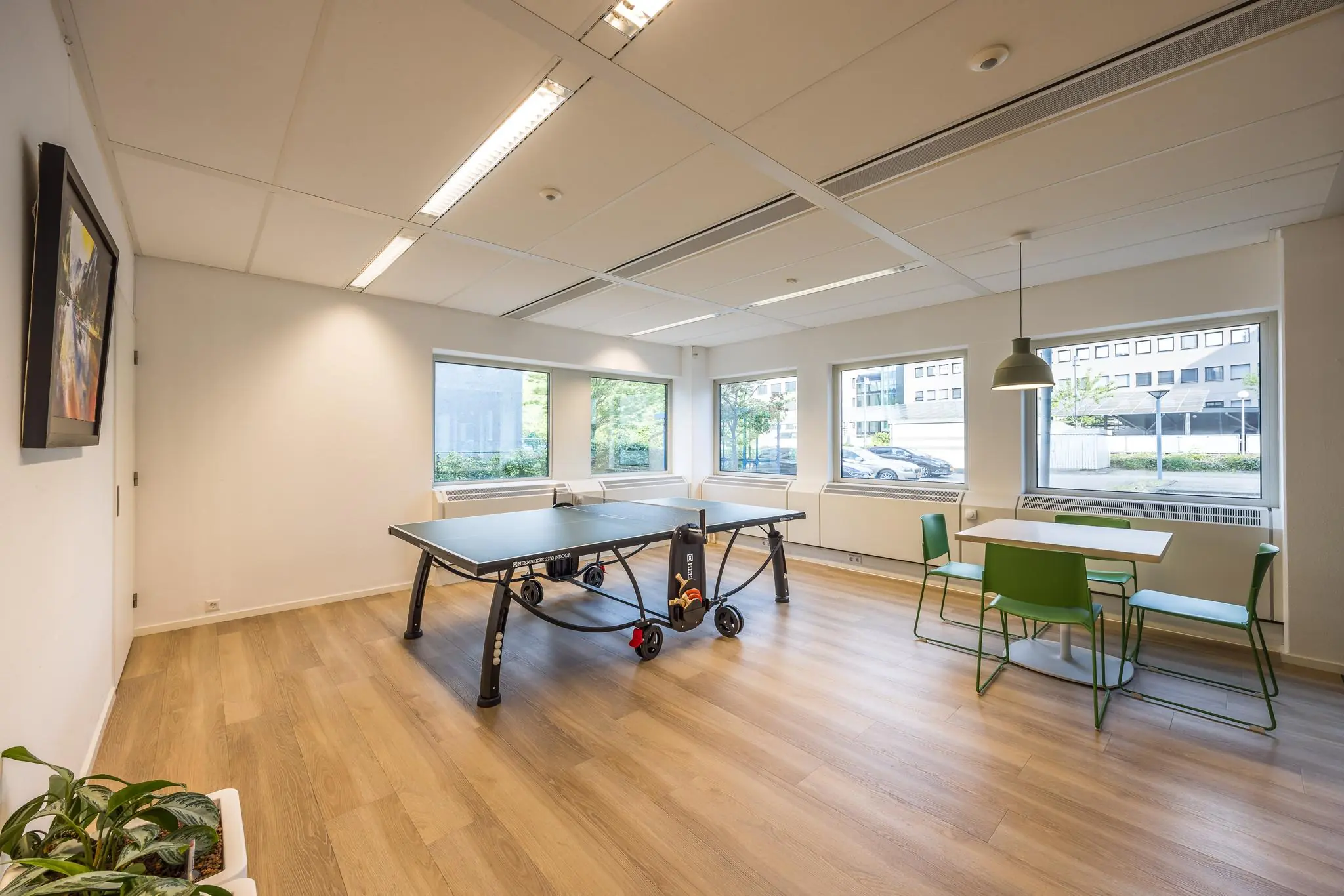 Moderne ontspanningsruimte met een tafeltennistafel en een zithoek met groene stoelen aan de Varrolaan.