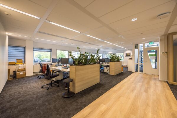 Moderne, open kantoortuin aan de Varrolaan met werkplekken, plantenbakken en grote ramen.