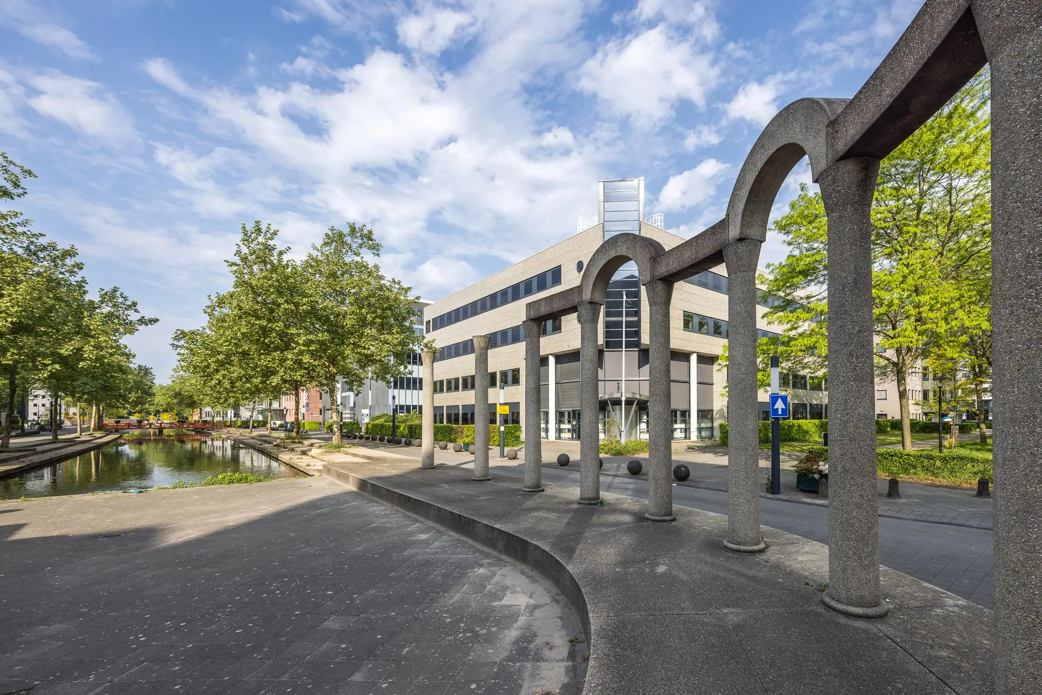 Moderne kantoorgebouwen aan de Varrolaan in Utrecht met een opvallende stenen boogconstructie en een waterpartij.
