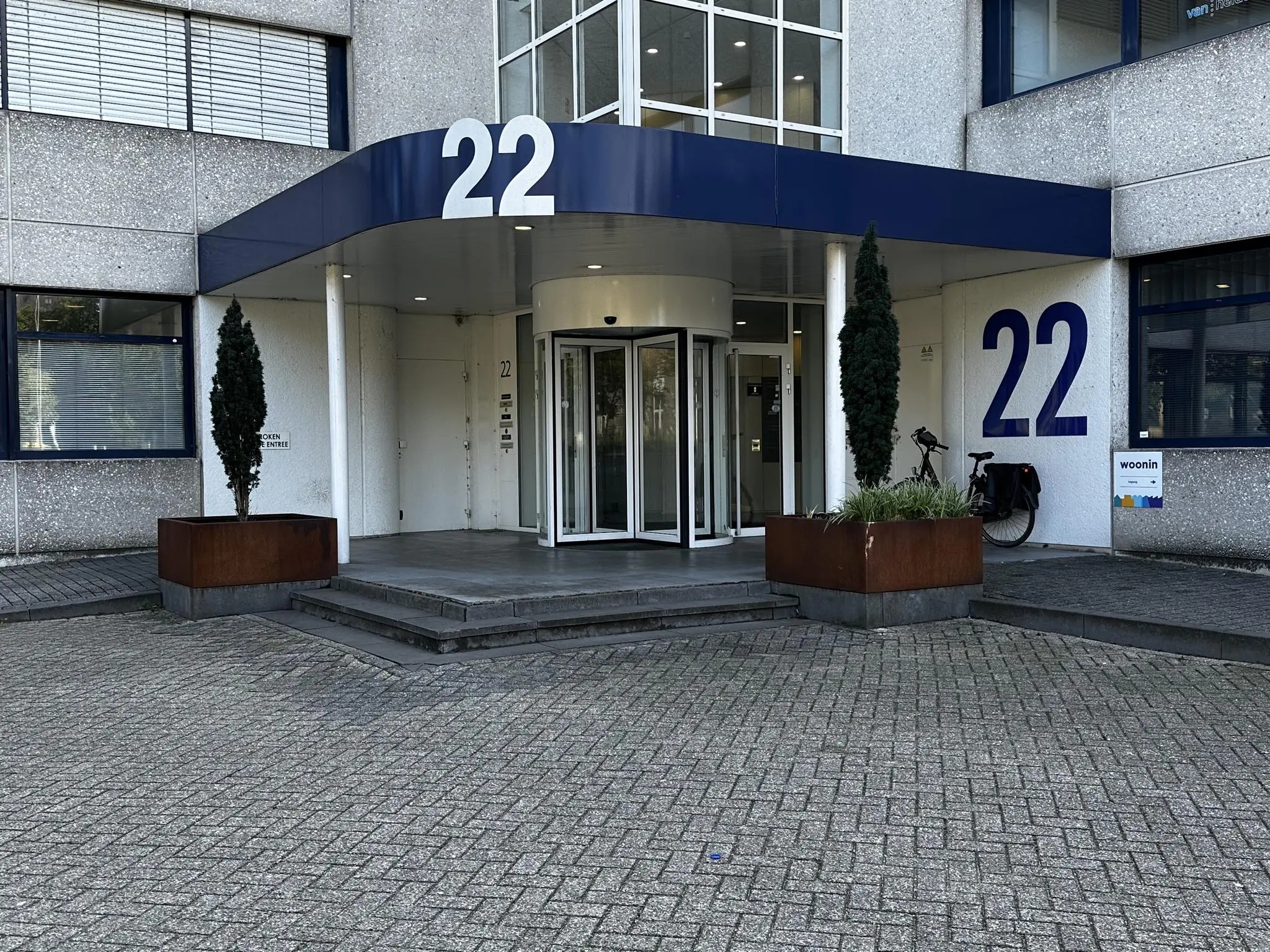 Ingang van een kantoorgebouw aan de Vreeswijksestraatweg 22 met draaideur, grote cijfers "22" en plantenbakken.
