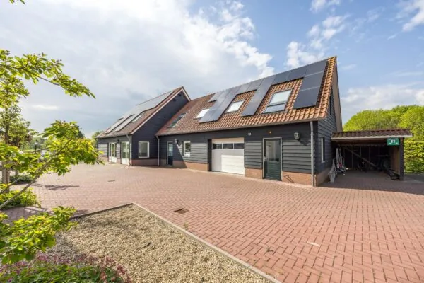 Moderne woning aan de Voorveste met zwarte gevelbekleding, zonnepanelen op het dak en een ruime oprit met carport.