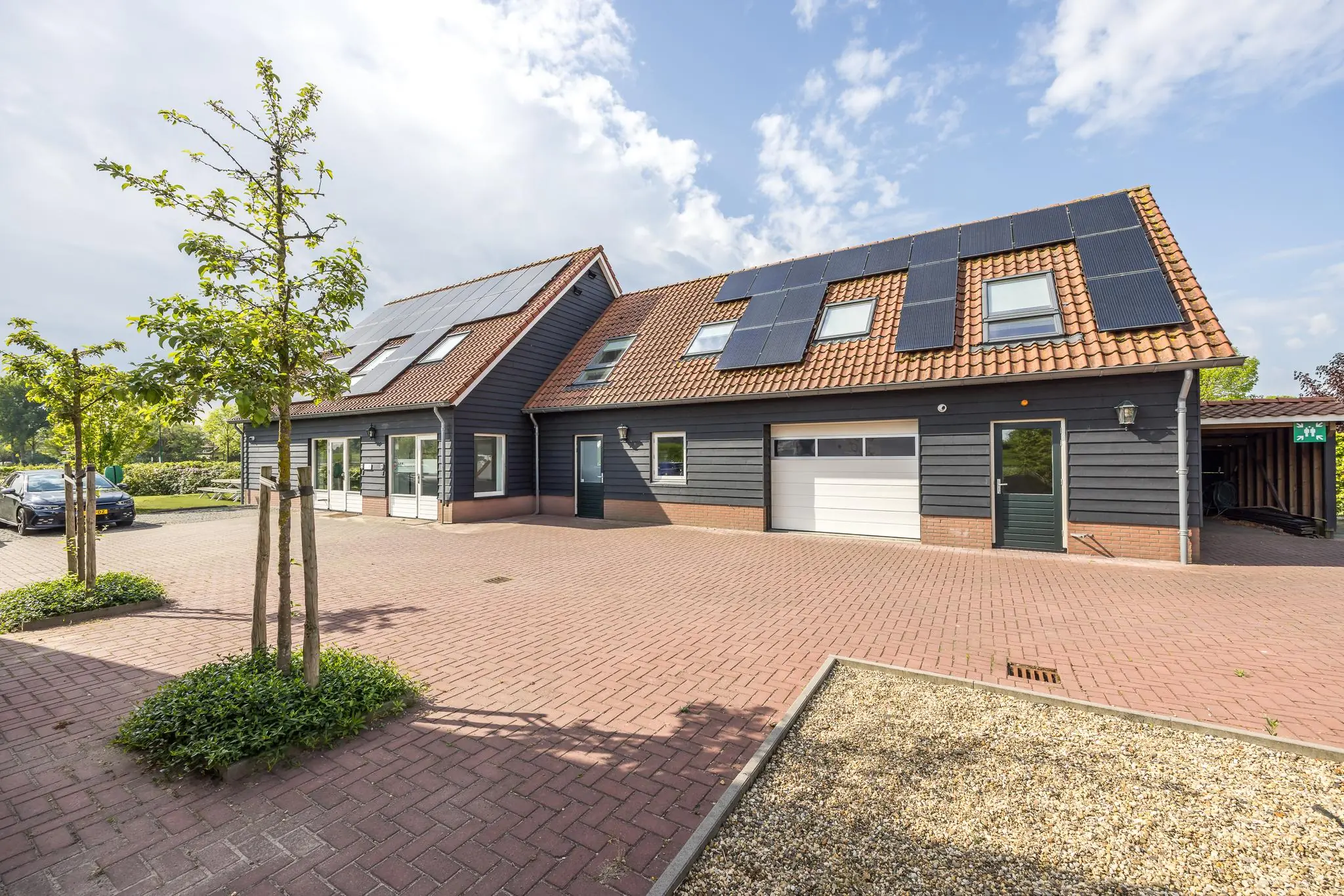 Moderne twee-onder-een-kapwoning aan de Voorveste met zwart houten gevels, rode dakpannen en zonnepanelen op het dak.