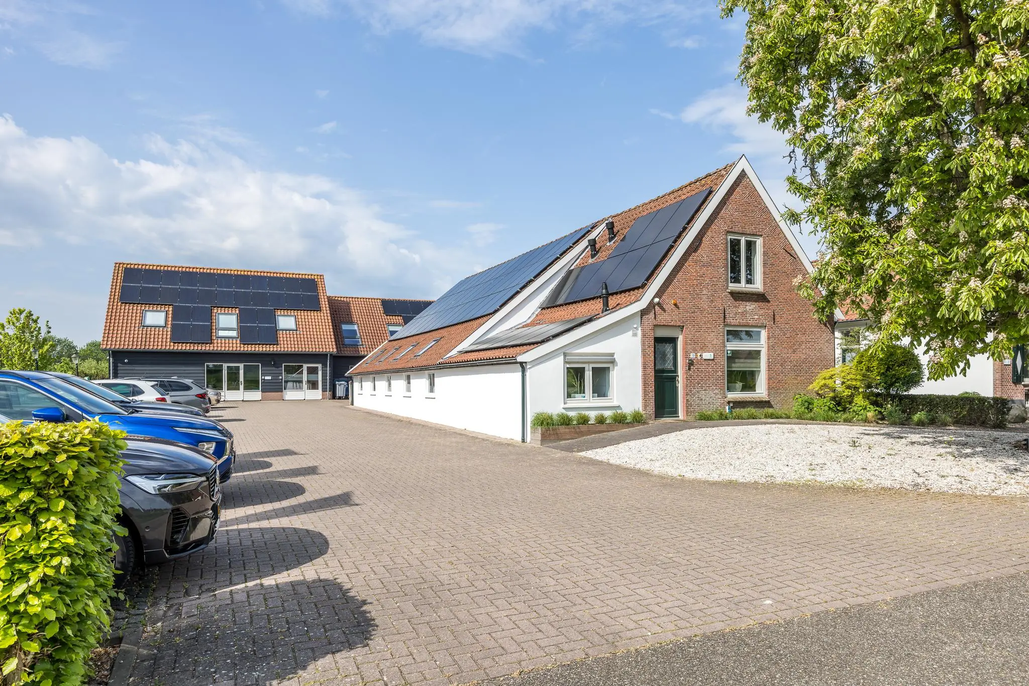 Modern gerenoveerde woning aan de Voorveste met zonnepanelen op het dak en een ruime oprit met geparkeerde auto's.