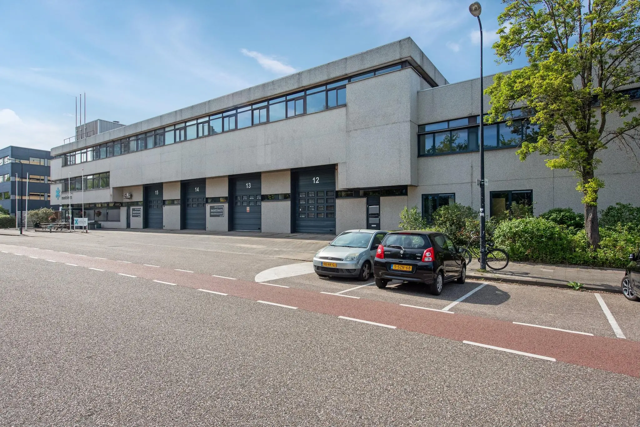 Kantoor- en bedrijfsgebouw aan de Limpergstraat met parkeervakken en laaddeuren genummerd 12 t/m 15.