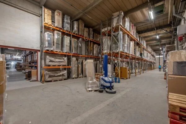 Ruime en goed georganiseerde opslaghal aan de Limpergstraat met stellingen vol verpakte goederen.