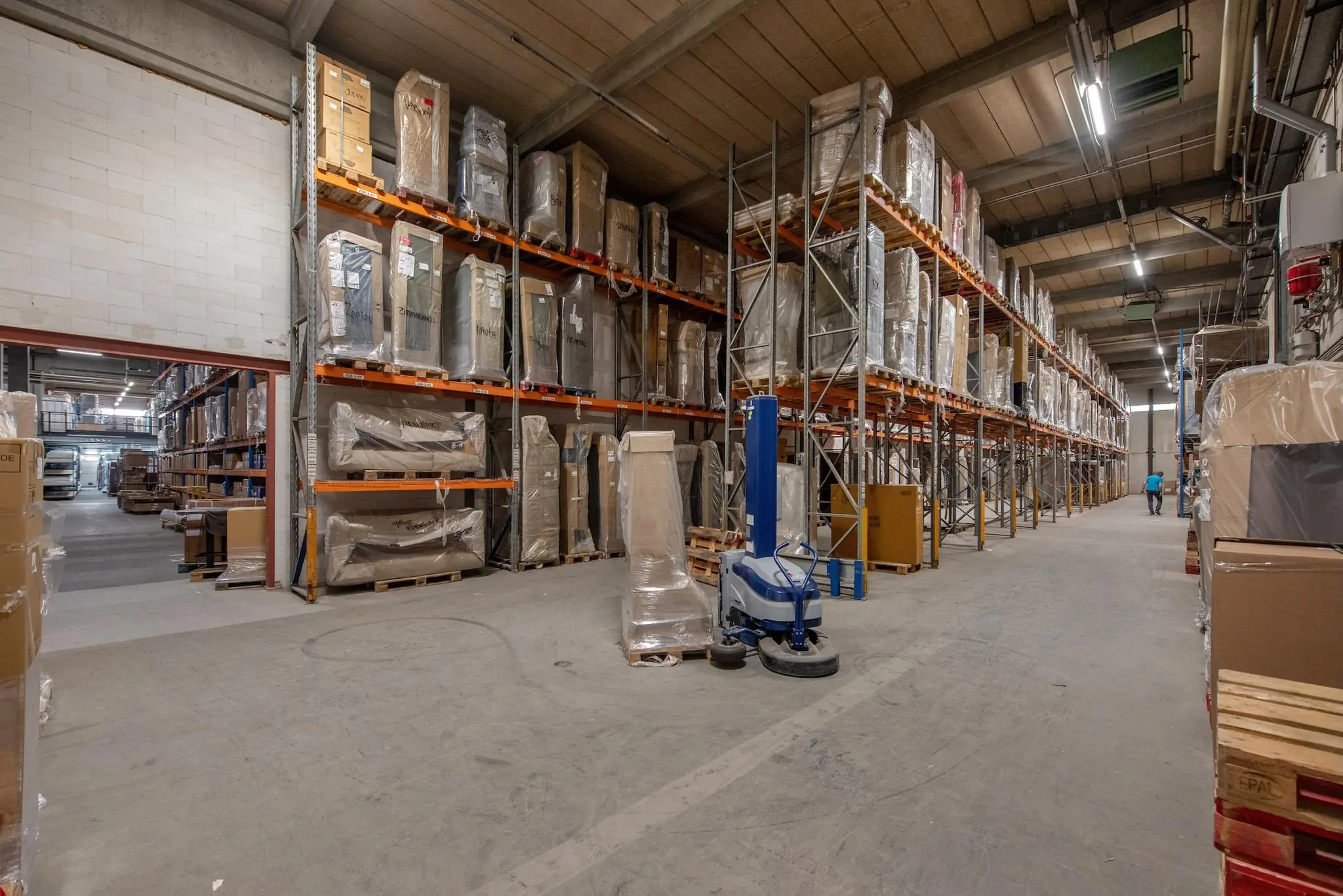 Ruime en goed georganiseerde opslaghal aan de Limpergstraat met stellingen vol verpakte goederen.