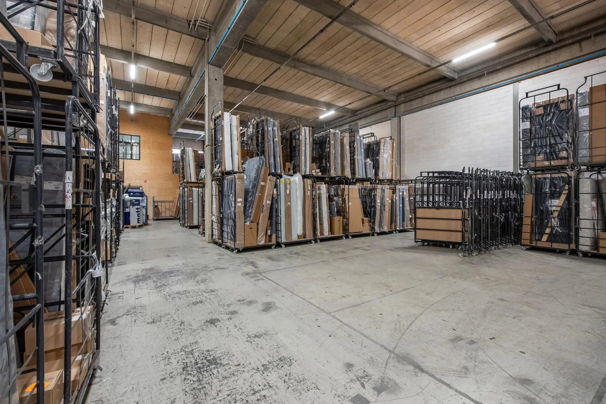 Opslagruimte aan de Limpergstraat met metalen karren vol verpakte goederen in een industriële hal.