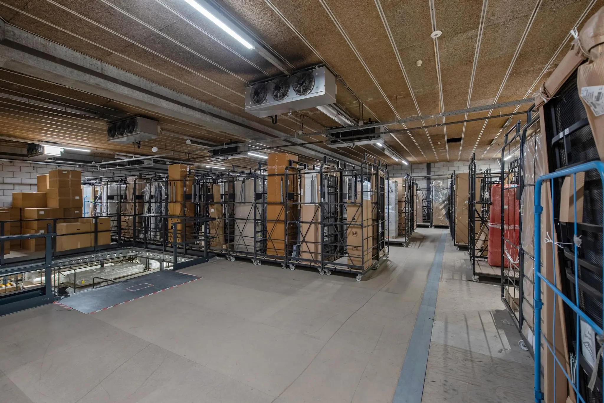 Opslagruimte met metalen rolcontainers en kartonnen dozen in een magazijn aan de Limpergstraat.