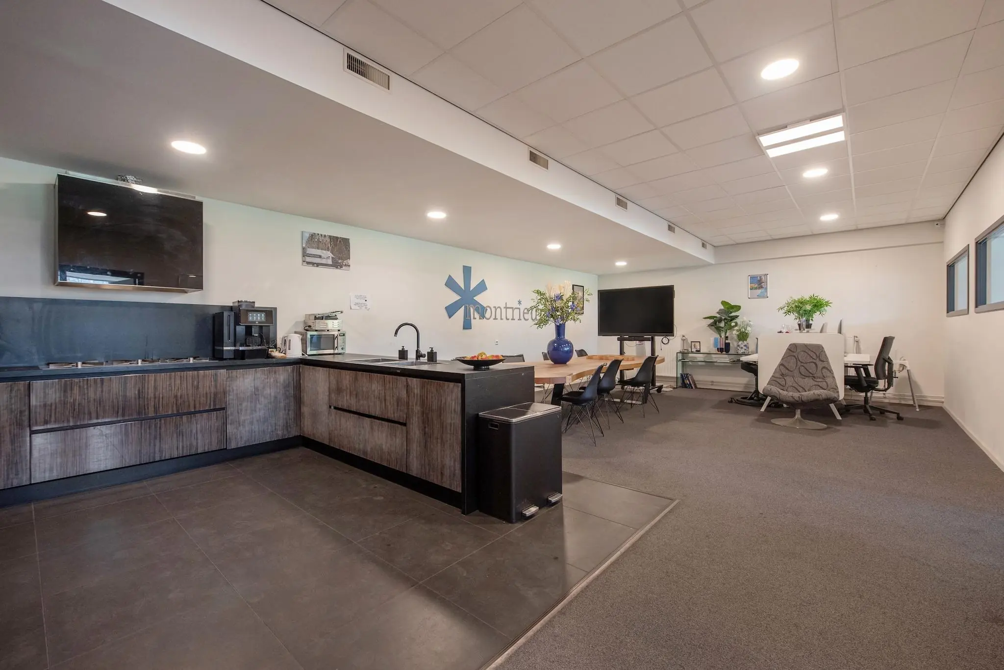 Moderne kantoorruimte aan de Limpergstraat met open keuken, vergadertafel en werkplekken.