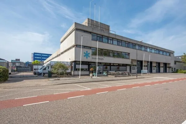Kantoorgebouw aan de Limpergstraat met bedrijfsnaam "Monteurs" op de gevel en meerdere laaddeuren aan de zijkant.