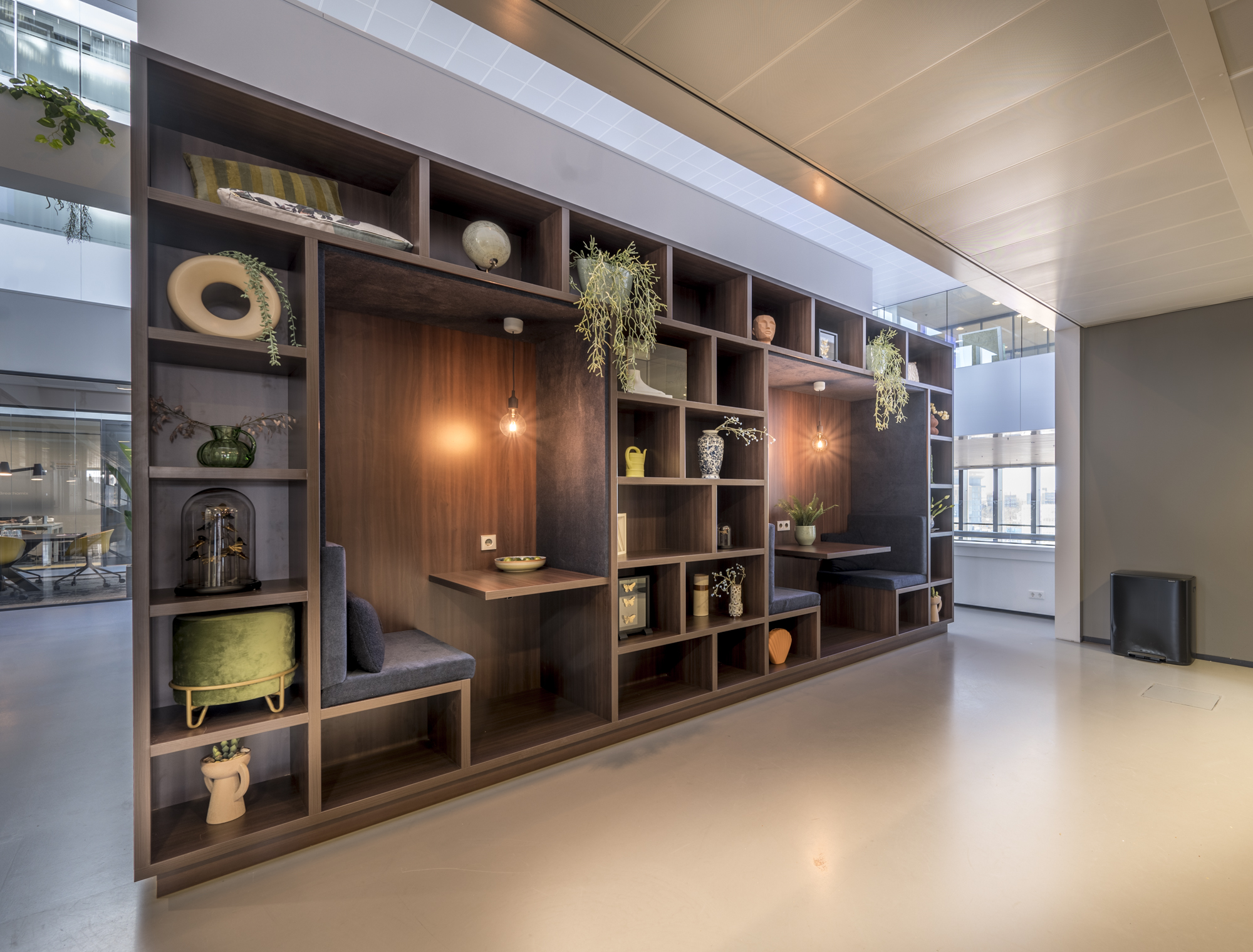 Een moderne bibliotheekwand met geïntegreerde zitplekken en decoratieve objecten.