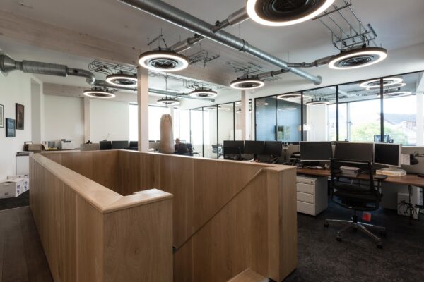 Modern kantoorinterieur aan de Fred. Roeskestraat met open werkplekken, houten trap en industriële verlichting.