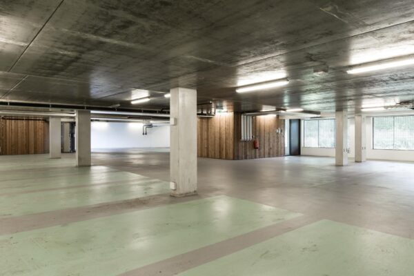 Ondergrondse parkeergarage aan de Fred. Roeskestraat met betonnen plafond, mintgroene parkeervakken en houten wandafwerking.