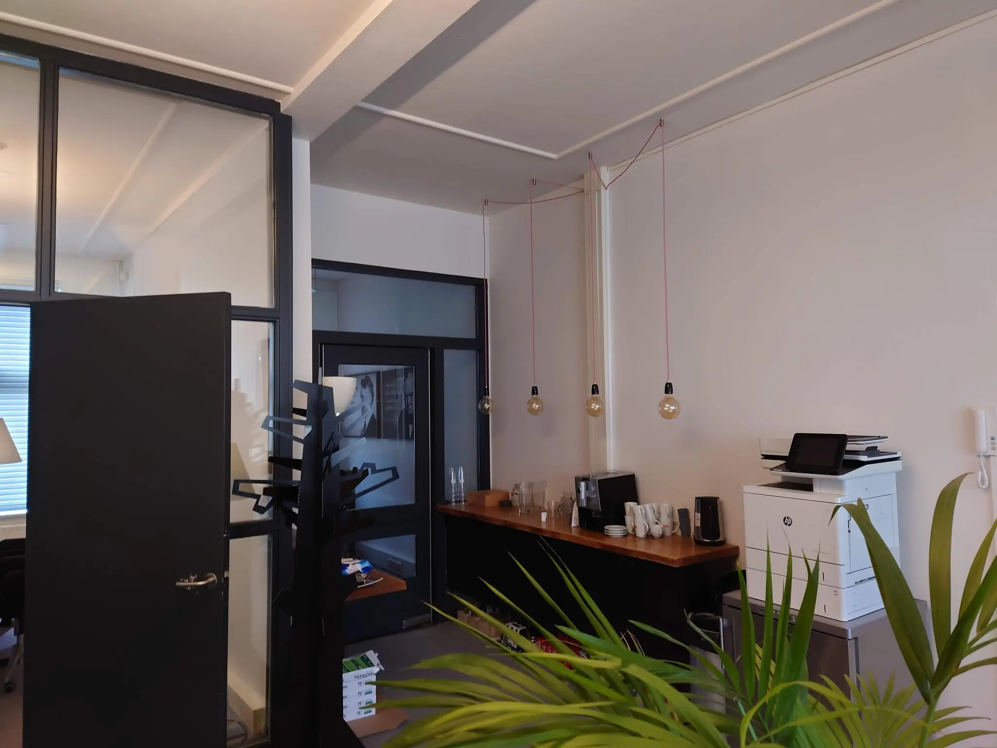 Moderne kantoorruimte aan de Maliesingel met koffiehoek, printer en minimalistische verlichting.