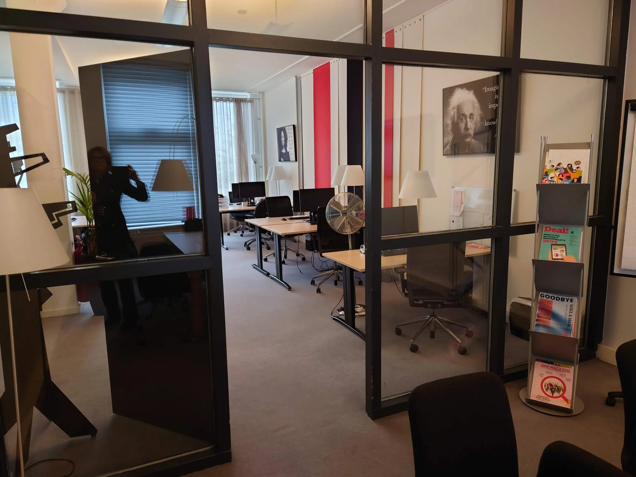 Moderne kantoorruimte aan de Maliesingel met glazen wanden, bureaus, tijdschriftenrek en een poster van Albert Einstein aan de muur.