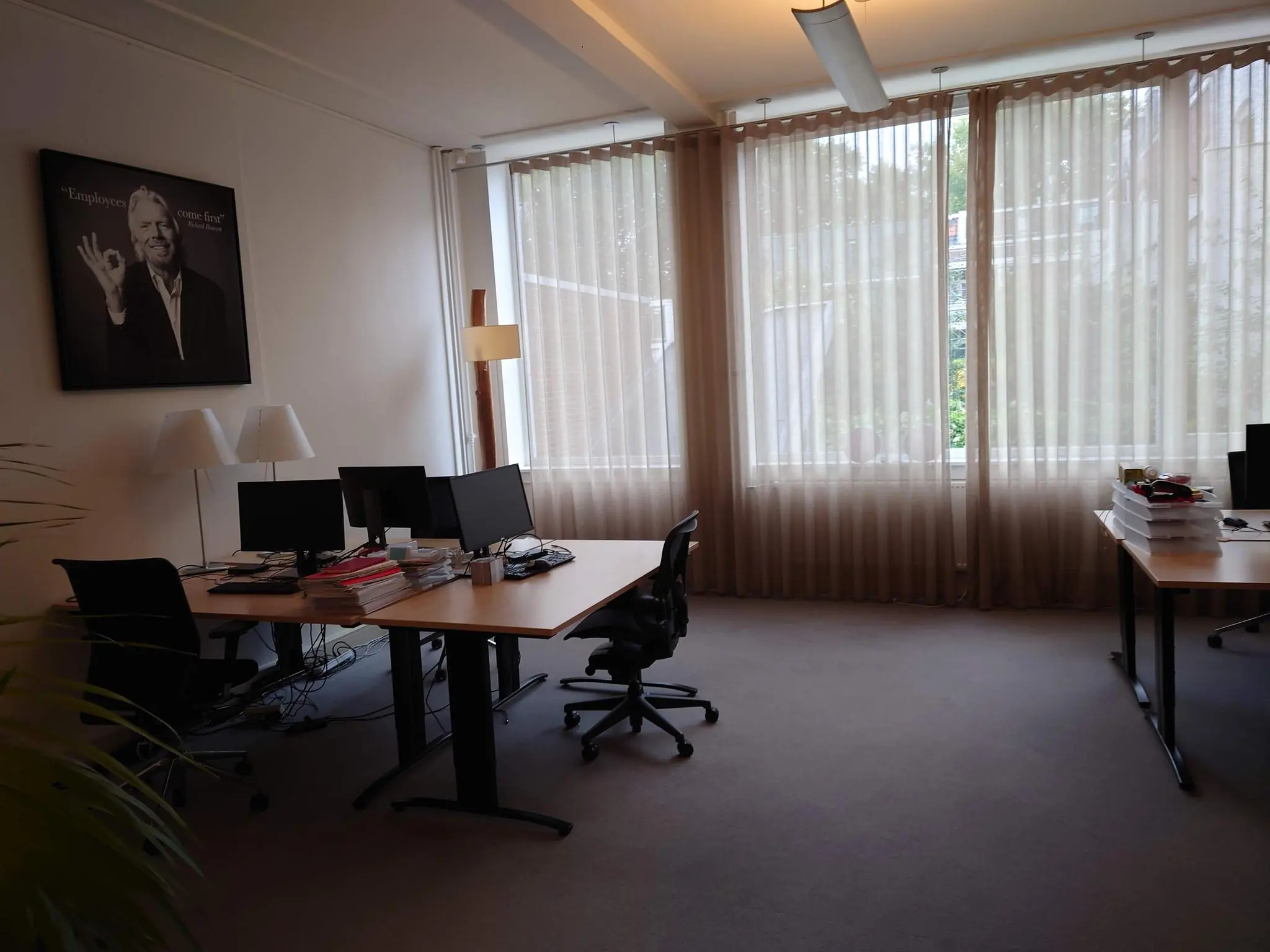 Een rustig, licht kantoor aan de Maliesingel met bureaus, computers en een grote foto aan de muur.