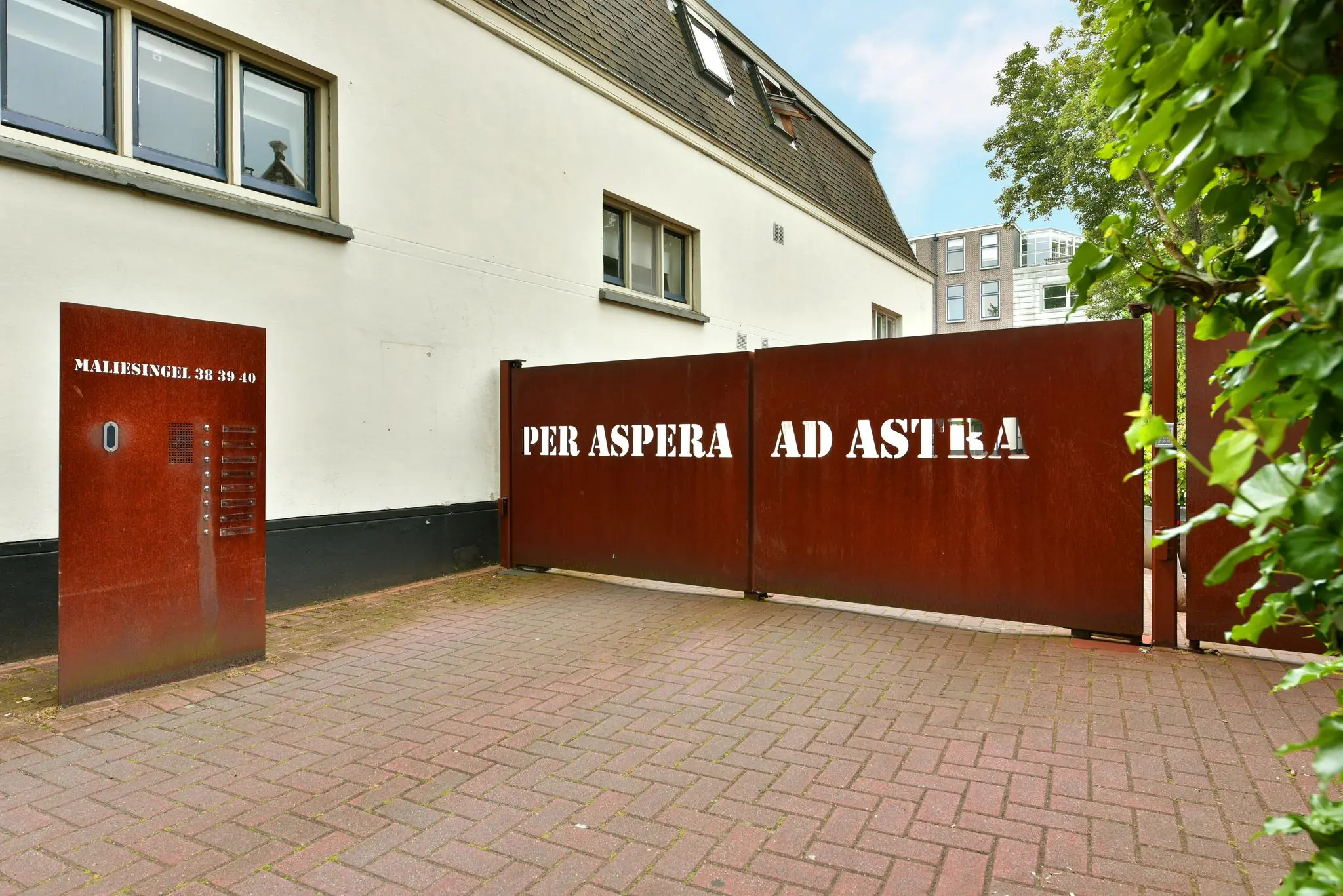 Rode metalen toegangspoort met de tekst "Per Aspera Ad Astra" bij de entree van Maliesingel 38-40.