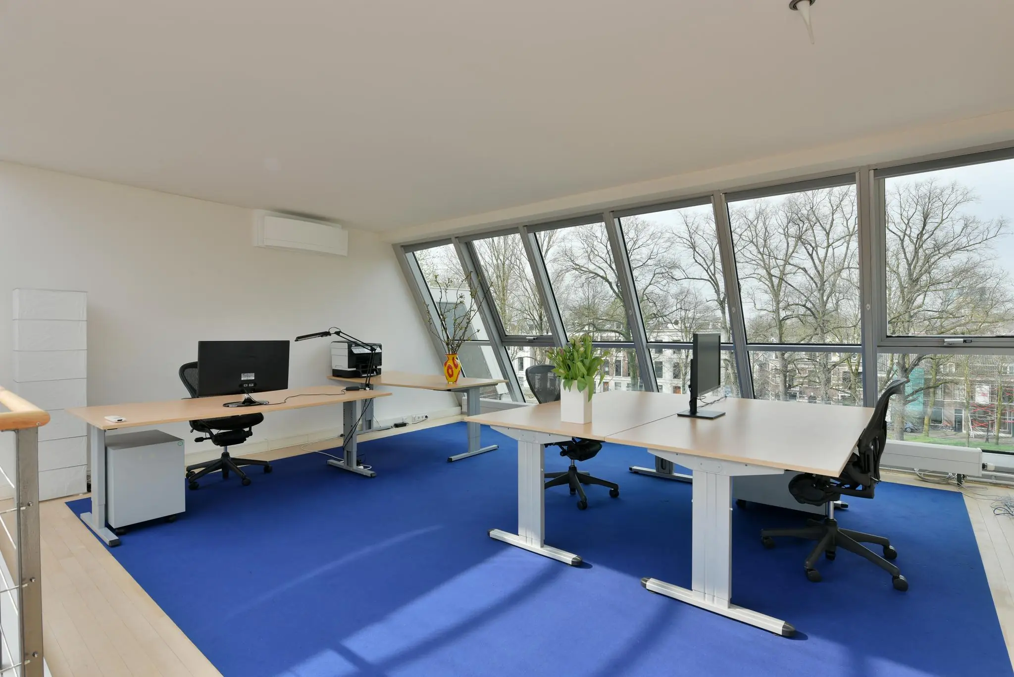 Modern kantoor op de Maliesingel met grote ramen, blauw tapijt en strak ingerichte werkplekken.