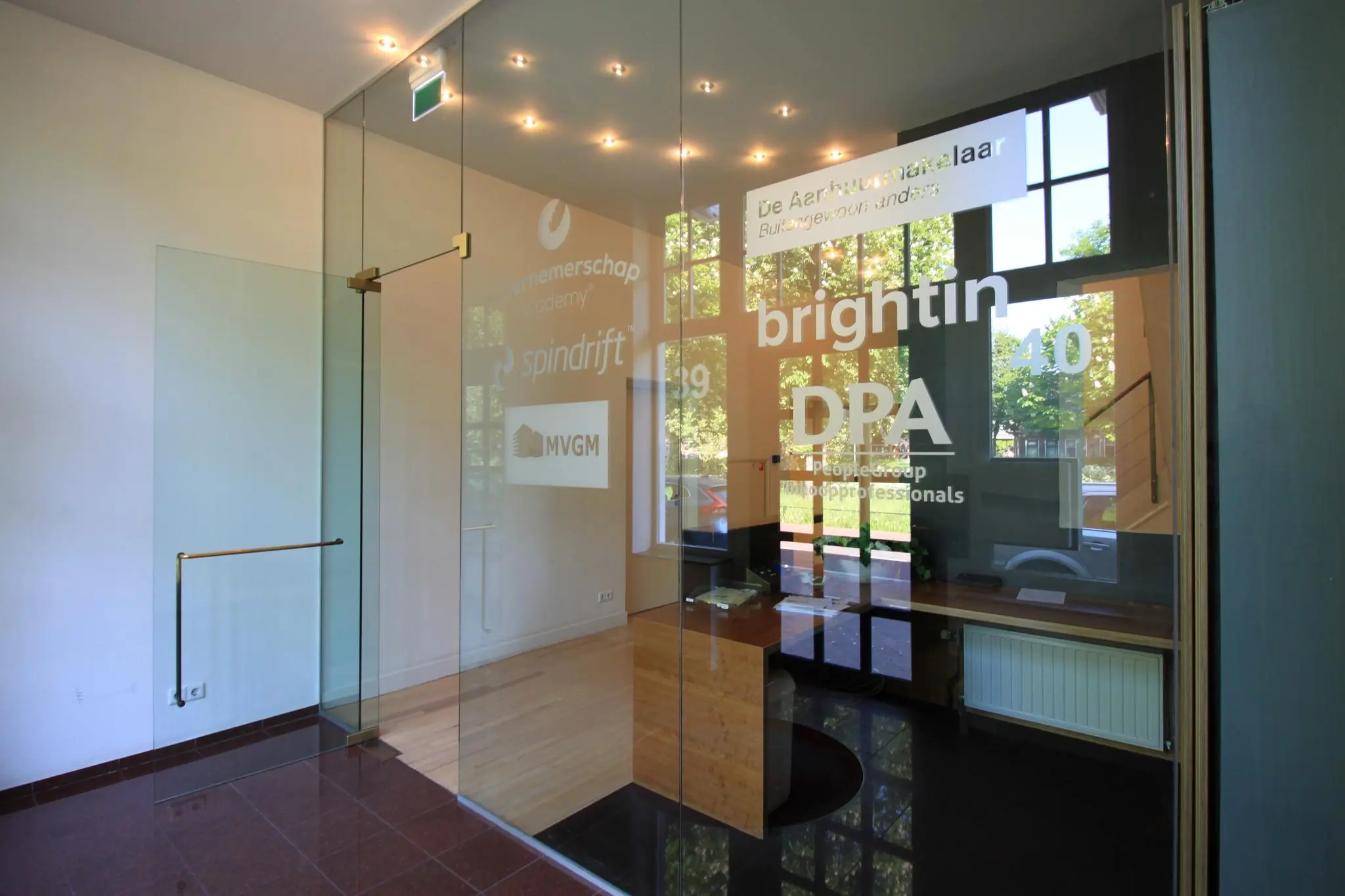 In een modern kantoorpand aan de Maliesingel zijn meerdere bedrijfsnamen zichtbaar op een glazen wand bij de entree.